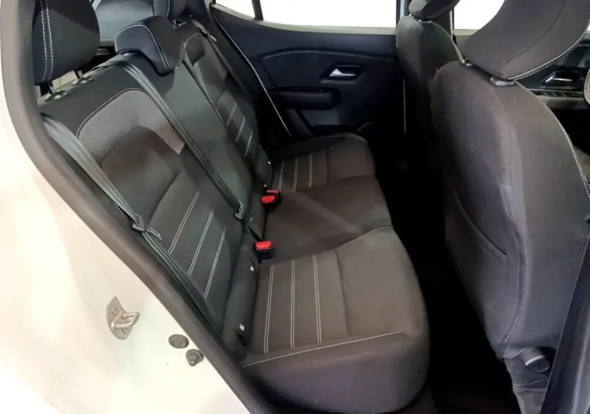 Vue intérieure côté gauche sur la banquette arrière noire avec surpiqûres blanches de la Dacia Sandero blanche.