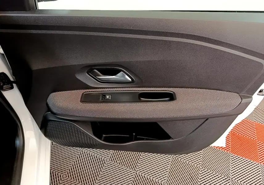 Vue rapprochée de la porte avant gauche blanche d’une Dacia Sandero 2022, avec panneau noir et insert gris texturé.