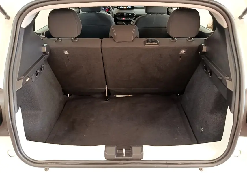 Coffre ouvert d'une Dacia Sandero blanc vue de l'arrière, montrant l'espace de chargement et la banquette arrière.