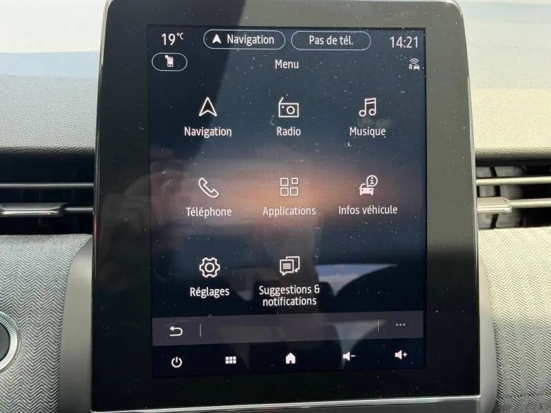 Écran tactile central du tableau de bord de la Renault Clio 1.6 E-Tech rouge, affichant le menu multimédia et navigation.