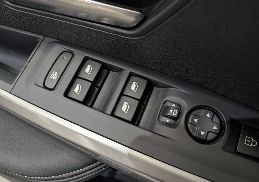 Gros plan sur les commandes des vitres et rétroviseurs côté gauche intérieur du Peugeot 3008 Hybrid 2026 finition Allure.