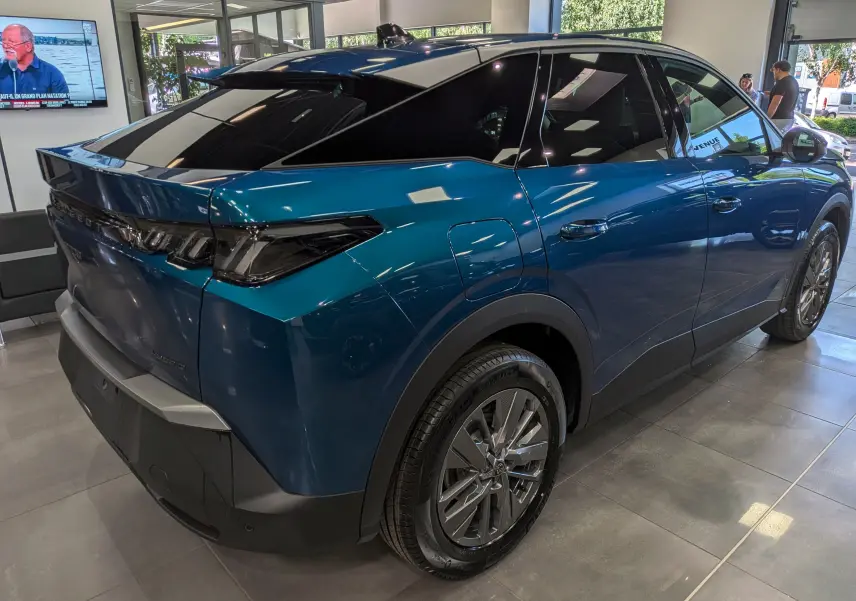 Vue 3/4 arrière droite du Peugeot 3008 Hybrid 145 ch bleu Obsession avec toit noir brillant en showroom.