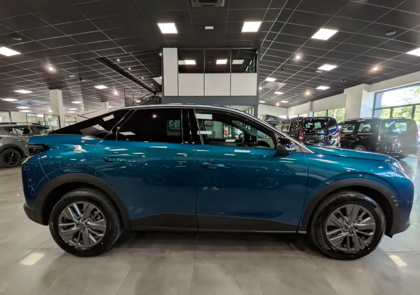Vue latérale droite d'un Peugeot 3008 Hybrid 145 ch bleu Obsession en showroom, soulignant ses jantes alliage et lignes modernes.
