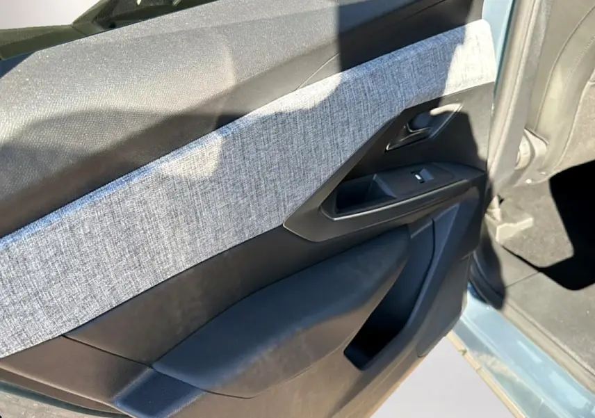Vue intérieure côté gauche de la porte avant d’un Peugeot 3008 bleu Ingara avec habillage tissu gris et plastique noir.