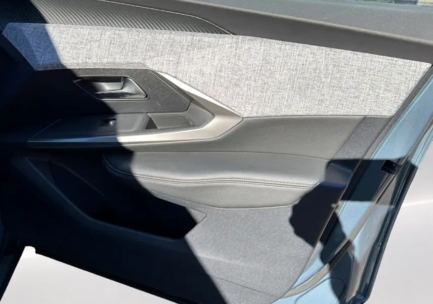 Vue rapprochée de la porte avant gauche du Peugeot 3008 2025 bleu ingaro, avec habillage tissu et cuir gris.