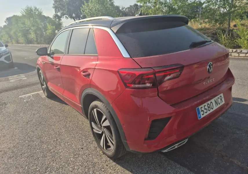 Vue 3/4 arrière droite d'un Volkswagen T-Roc rouge métal foncé avec toit noir et jantes alliage noires.