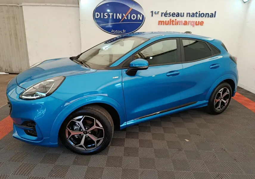 Vue latérale droite d'un Ford Puma bleu 2025 ST-LINE avec jantes alliage et vitres teintées en intérieur showroom.