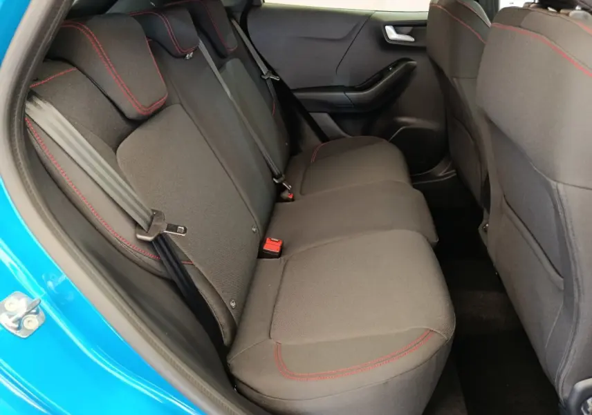 Vue intérieure côté gauche sur la banquette arrière noire avec surpiqûres rouges du Ford Puma bleu 2025 ST-LINE.