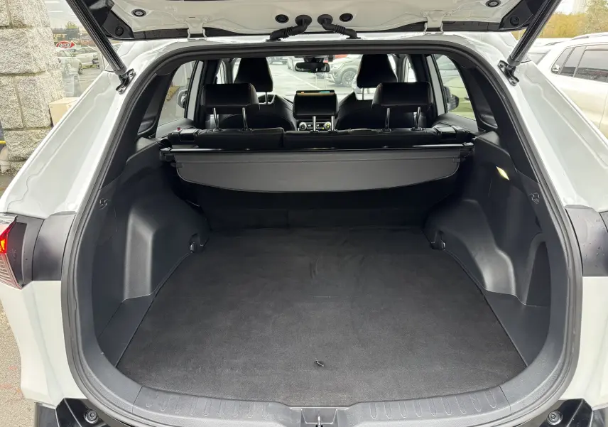 Coffre ouvert vu de l'arrière d'un Suzuki Across blanc 2023, montrant l'espace de chargement et l'intérieur noir.