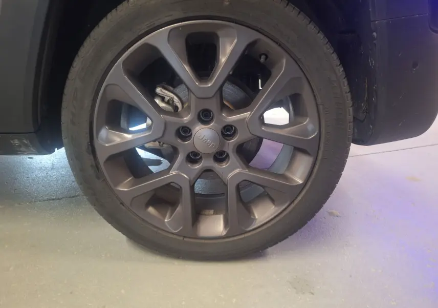 Gros plan sur la roue avant droite du Jeep Renegade noir 2024, mettant en valeur la jante alliage 19 pouces au design moderne.