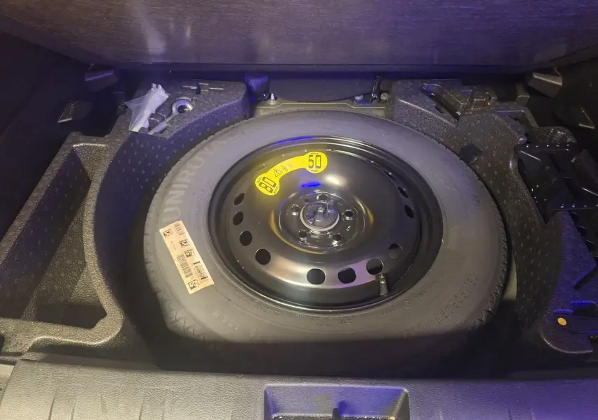 Vue plongeante sur la roue de secours noire dans le coffre du Jeep Renegade 2024 hybride noir.