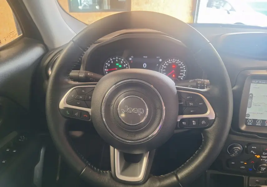 Vue centrée sur le volant noir en cuir du Jeep Renegade 2024, avec tableau de bord et écran tactile visibles à droite.