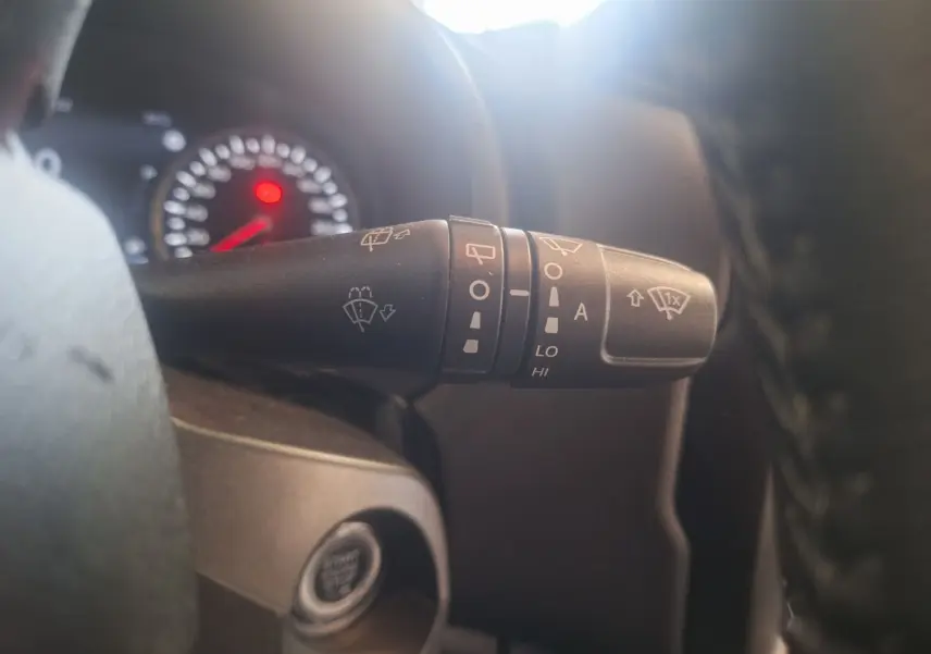 Gros plan sur le commodo d'essuie-glace à gauche du volant dans l'habitacle noir du Jeep Renegade 2024.