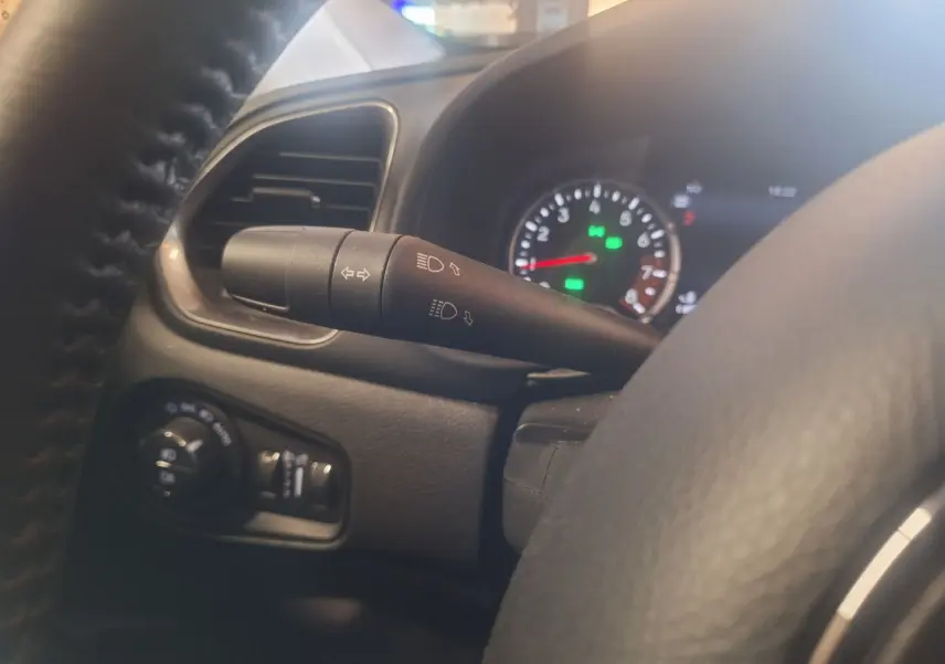 Détail du commodo d'éclairage côté gauche du tableau de bord noir du Jeep Renegade 2024 hybride.