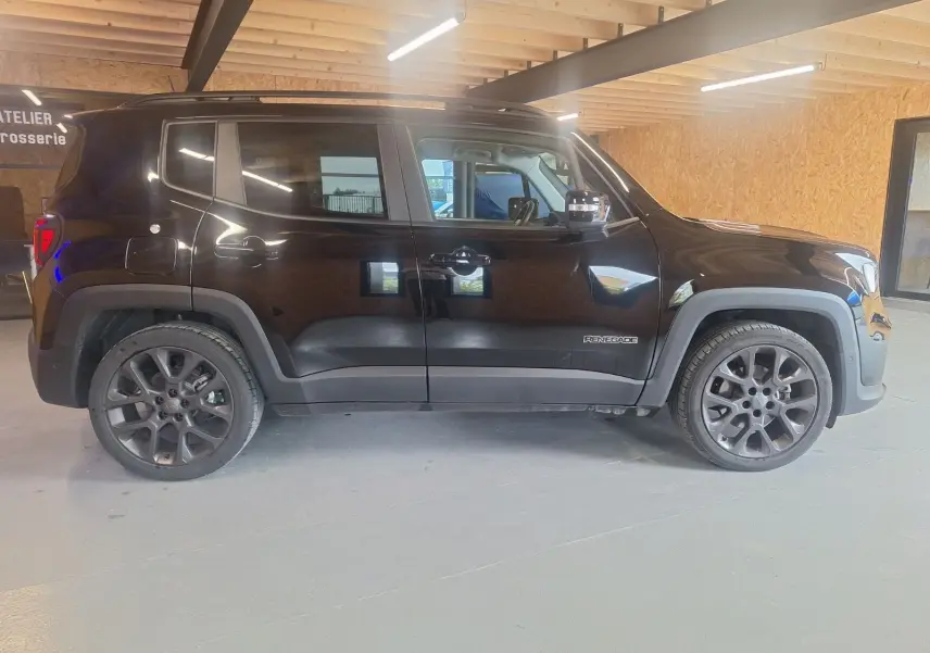 Profil côté gauche d'un Jeep Renegade noir 2024 en version hybride, avec jantes foncées et détails de carrosserie marqués.