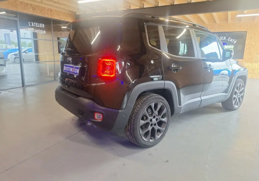 Jeep Renegade noir en vue 3/4 arrière droit, avec feux arrière allumés et jantes alliage 19 pouces visibles.