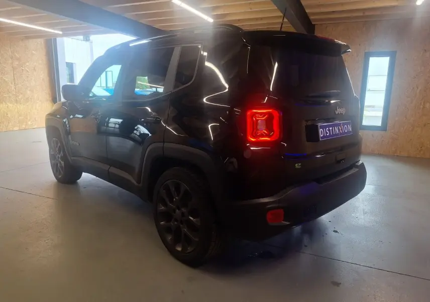 Jeep Renegade noir en 3/4 arrière droit dans un garage, avec feux arrière allumés et jantes foncées.