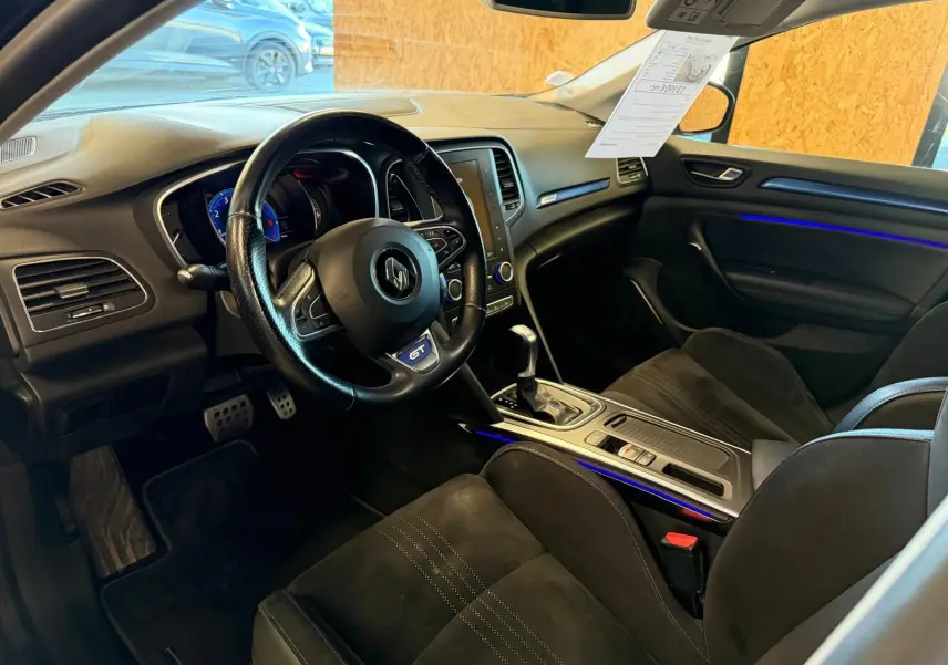 Intérieur noir de Renault Mégane Break GT 2017 vu côté conducteur, avec éclairage d’ambiance bleu et volant GT.