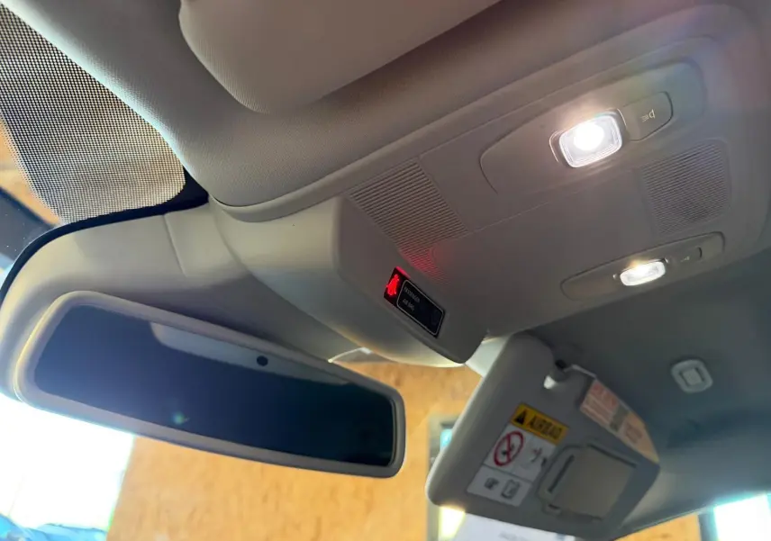 Vue intérieure en contre-plongée du rétroviseur central et du plafonnier éclairé d'une Renault Mégane Break gris 2017.