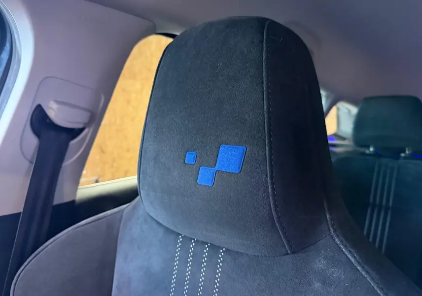 Gros plan sur l’appui-tête avant noir en tissu avec logo bleu, intérieur de la Renault Mégane Break GT 2017.