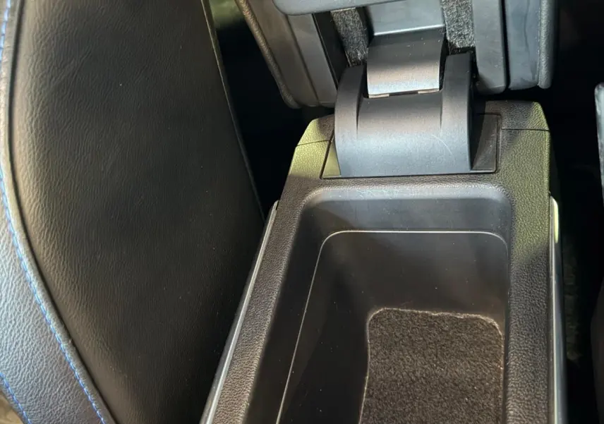 Vue rapprochée de l'accoudoir central ouvert avec rangement intérieur sur Renault Mégane Break gris, intérieur noir.