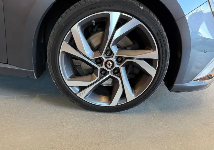 Gros plan sur la roue avant droite grise d'une Renault Mégane Break GT 2017 avec jante alliage marquée GT.