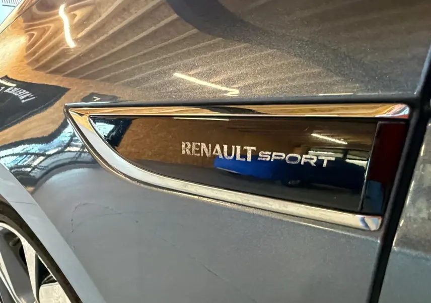 Gros plan sur l’inscription Renault Sport sur la carrosserie grise d’un Renault Mégane Break GT, côté avant droit.