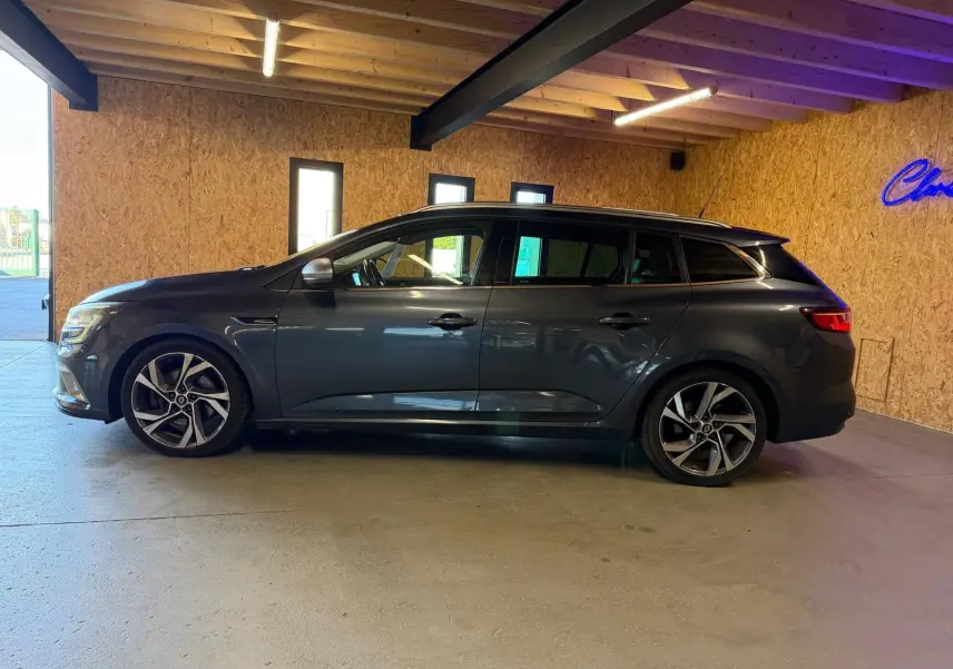 Renault Mégane Break GT gris vue de profil côté gauche, stationnée dans un garage avec murs en bois.