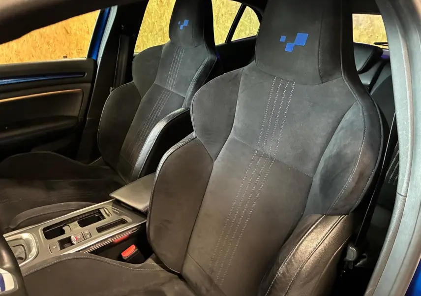 Vue intérieure rapprochée des sièges avant noirs en alcantara avec logo bleu sur appuie-tête d’une Renault Mégane GT Line 2019.