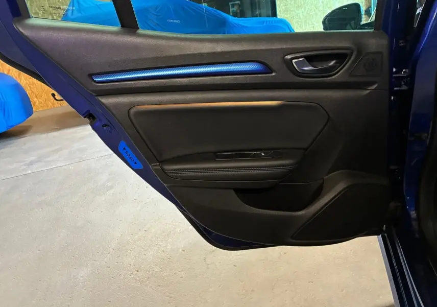 Vue rapprochée de la porte arrière gauche bleu foncé de la Renault Mégane 2019 avec insert décoratif bleu et poignée noire.