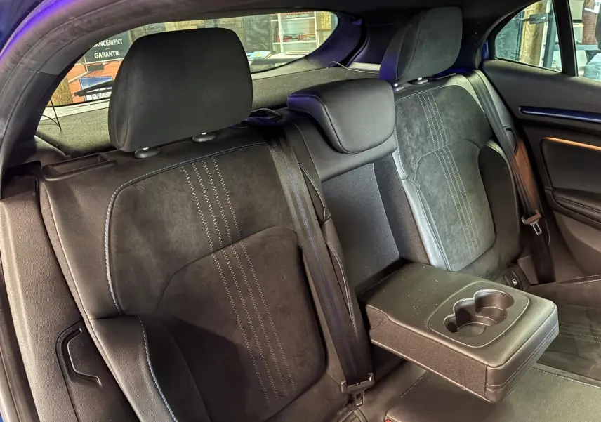 Vue intérieure arrière gauche des sièges noirs en cuir et alcantara de la Renault Mégane 2019 avec accoudoir central et porte-gobelets.
