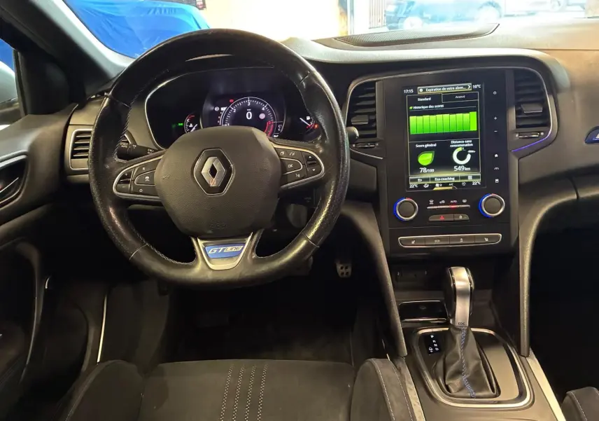 Vue intérieure frontale du poste de conduite d'une Renault Mégane GT Line 2019 avec volant cuir noir et écran tactile central allumé.