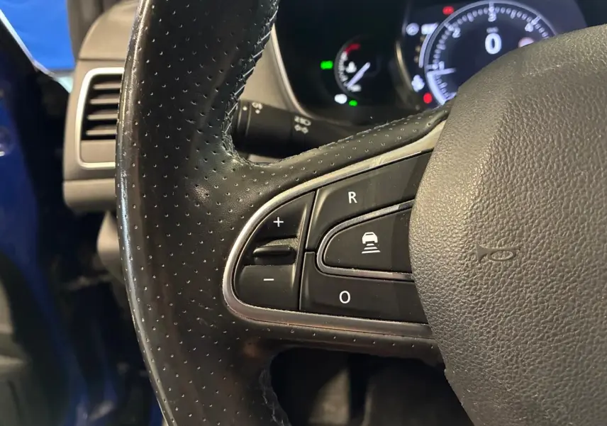 Gros plan sur le volant en cuir perforé noir de la Renault Mégane 1.7 BlueDCI 150 GT Line, avec commandes intégrées.