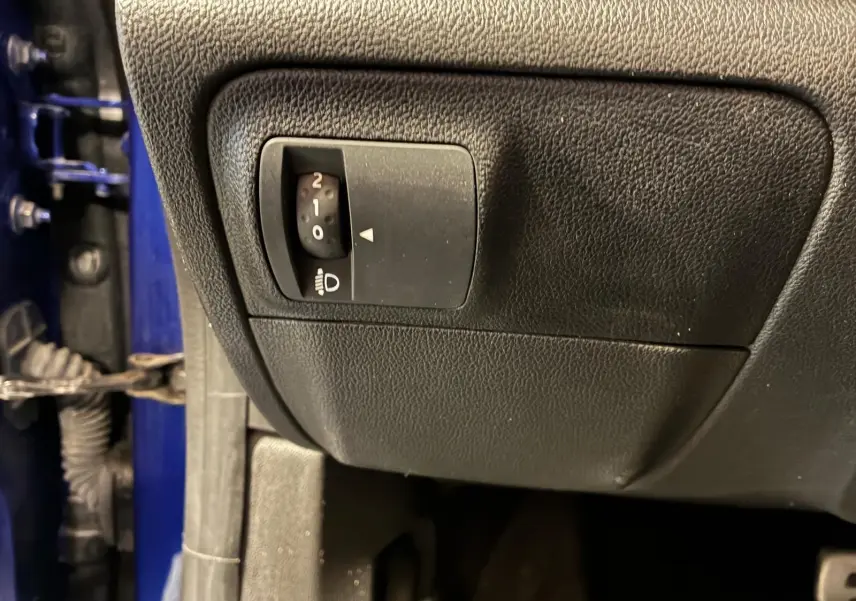 Gros plan sur le réglage d'inclinaison des phares côté gauche, avec une partie de la carrosserie bleu visible.