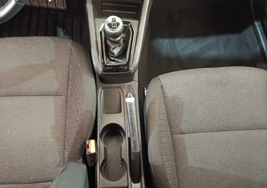 Vue intérieure centrée sur la console centrale et levier de vitesse manuel, sièges tissu gris foncé de la Renault Clio Business.