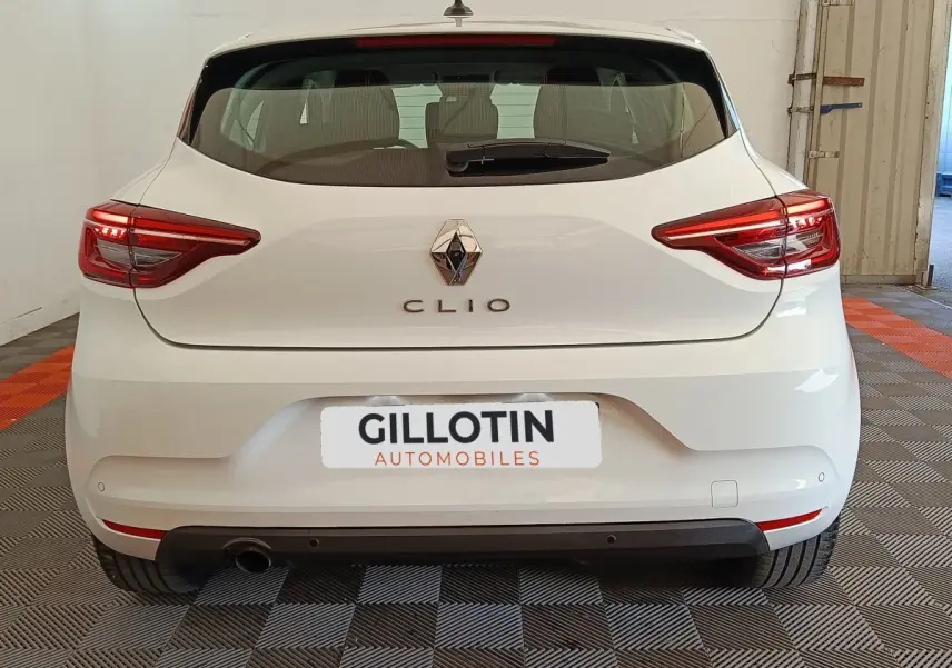 Vue arrière d'une Renault Clio blanche 2022 avec feux LED et logo Renault visible sur un sol damier intérieur.