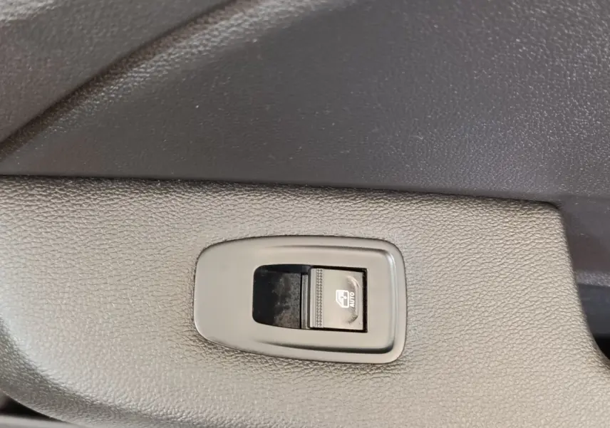 Gros plan sur le bouton de commande de la vitre électrique côté conducteur, intérieur noir texturé de Renault Clio blanc 2022.