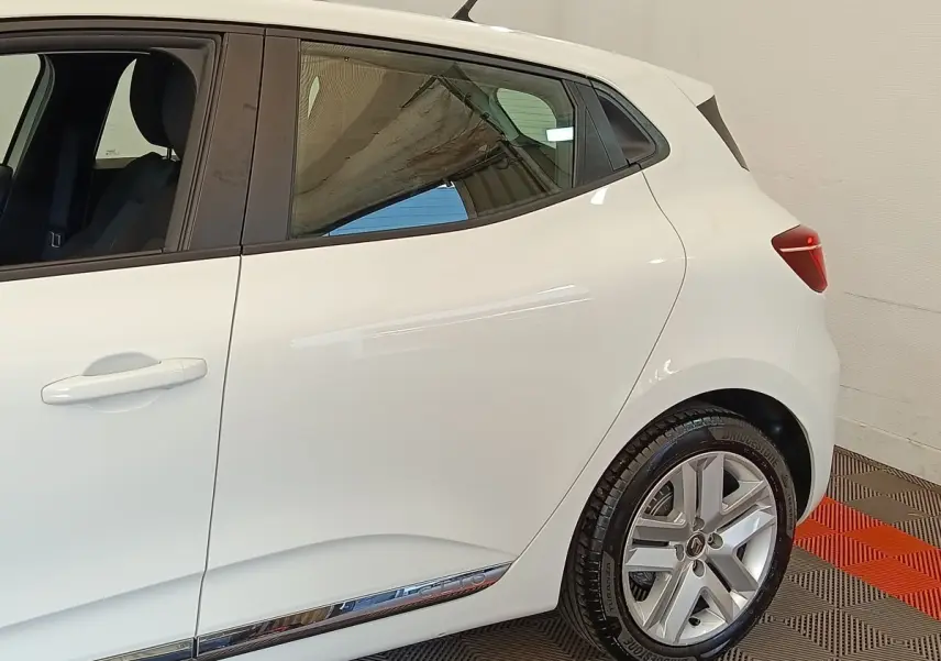 Vue côté droit arrière d'une Renault Clio Business Blue dCi 100 blanche avec jantes alliage et poignées de porte ton carrosserie.