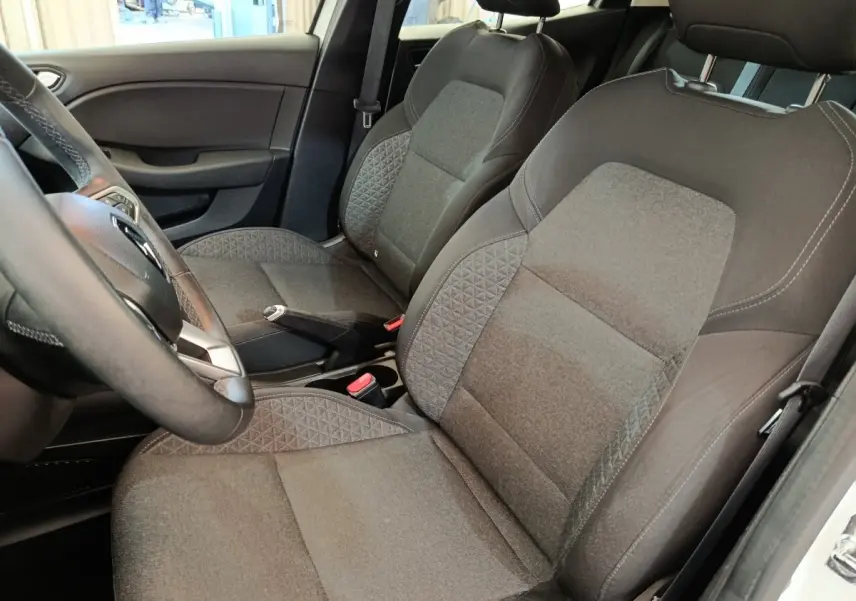 Vue intérieure côté conducteur de la Renault Clio Business Blue dCi 100 2022, sièges tissu gris et volant cuir synthétique.