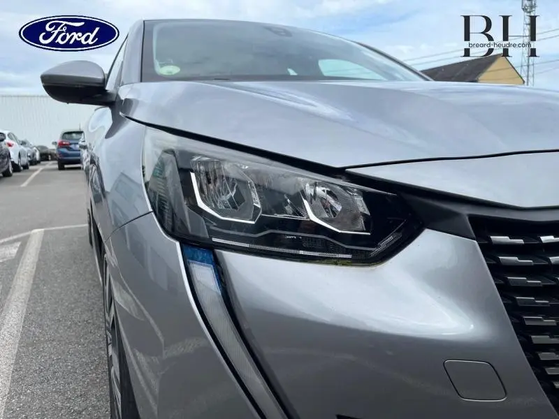 Gros plan sur le phare avant droit de la Peugeot 208 gris Artense, soulignant son design moderne et ses lignes précises.