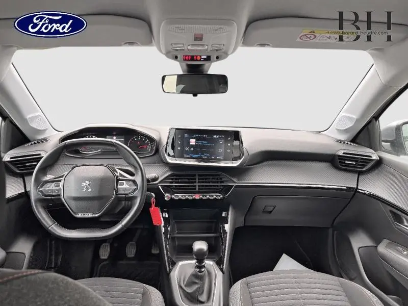 Vue intérieure avant du Peugeot 208 gris Artense 2020, avec tableau de bord moderne et boîte manuelle visible.