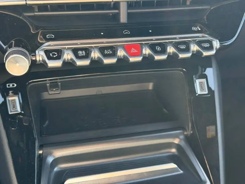 Vue rapprochée de la console centrale noire du Peugeot 2008 2024 avec rangée de boutons chromés et touches fonctionnelles.