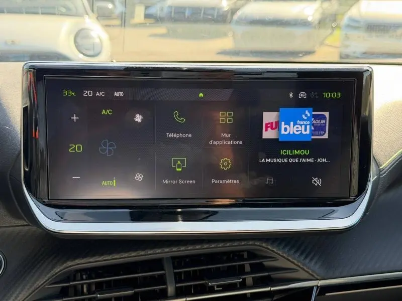 Écran tactile multifonction du tableau de bord du Peugeot 2008 gris, affichant la radio et les réglages climatiques.