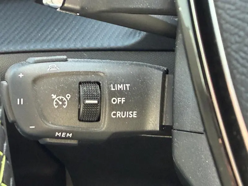 Gros plan sur la commande de régulateur de vitesse noire dans l'habitacle du Peugeot 2008 gris 2024.