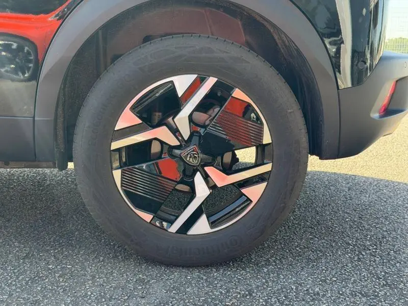 Gros plan sur la roue avant droite du Peugeot 2008 gris, mettant en valeur la jante alu au design moderne bicolore.