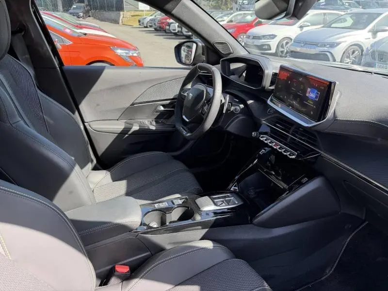 Vue intérieure côté conducteur de la Peugeot 2008 gris, avec volant cuir multifonction et écran tactile central.