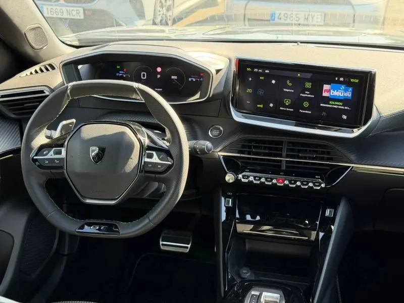 Vue intérieure du poste de conduite du Peugeot 2008 gris 2024, avec volant cuir multifonction et écran tactile central.