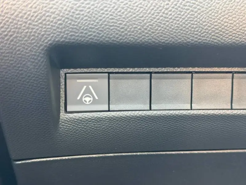 Bouton de contrôle d'aide au maintien de voie sur tableau de bord noir d'une Peugeot 2008 gris Selenium.