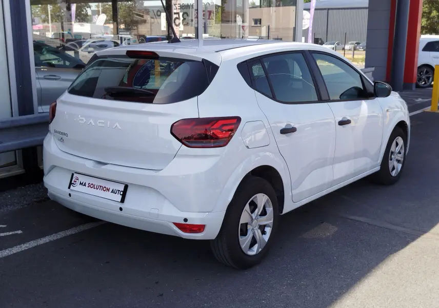 Vue 3/4 arrière droite d'une Dacia Sandero blanche Glacier 2025 avec feux arrière LED et jantes acier.