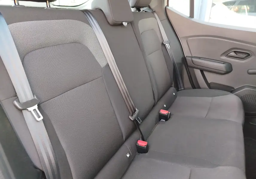 Vue latérale droite de la banquette arrière en tissu gris foncé de la Dacia Sandero 2025, avec ceintures et appuie-têtes visibles.